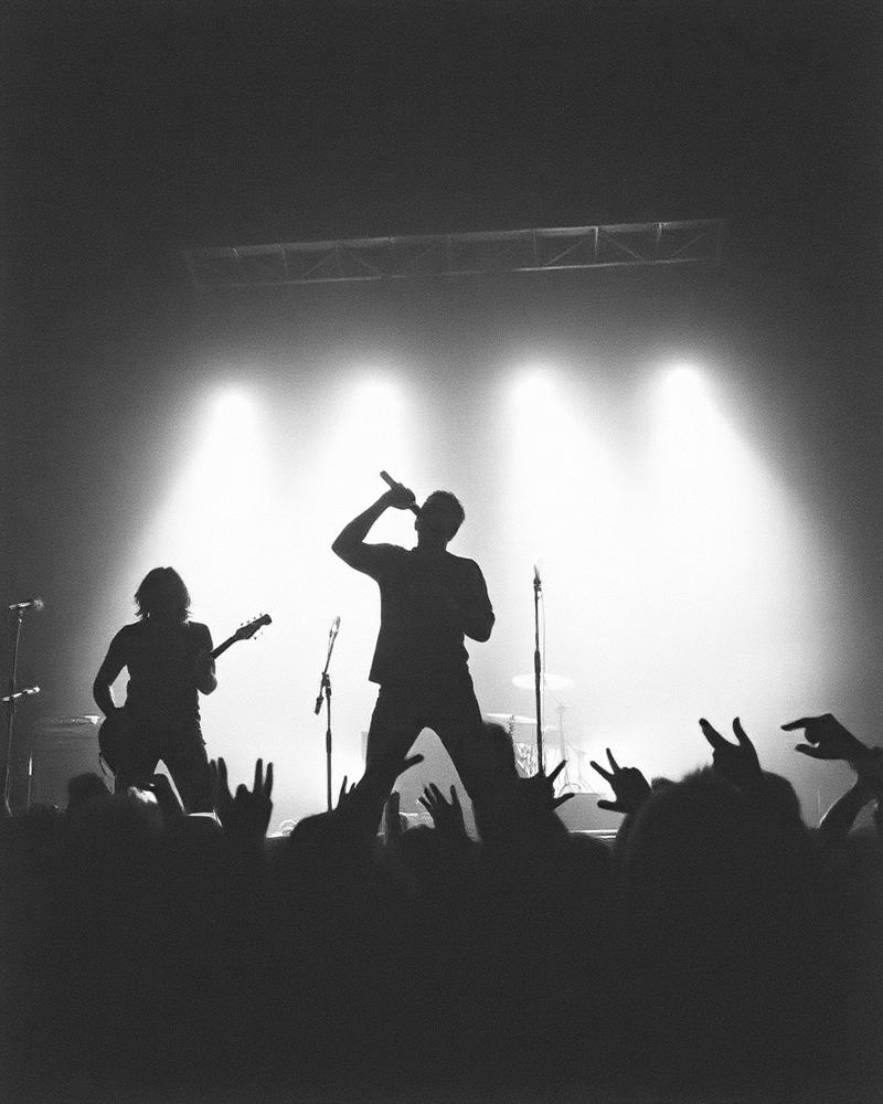 Silhouetted punk band on stage under blown-out white lights